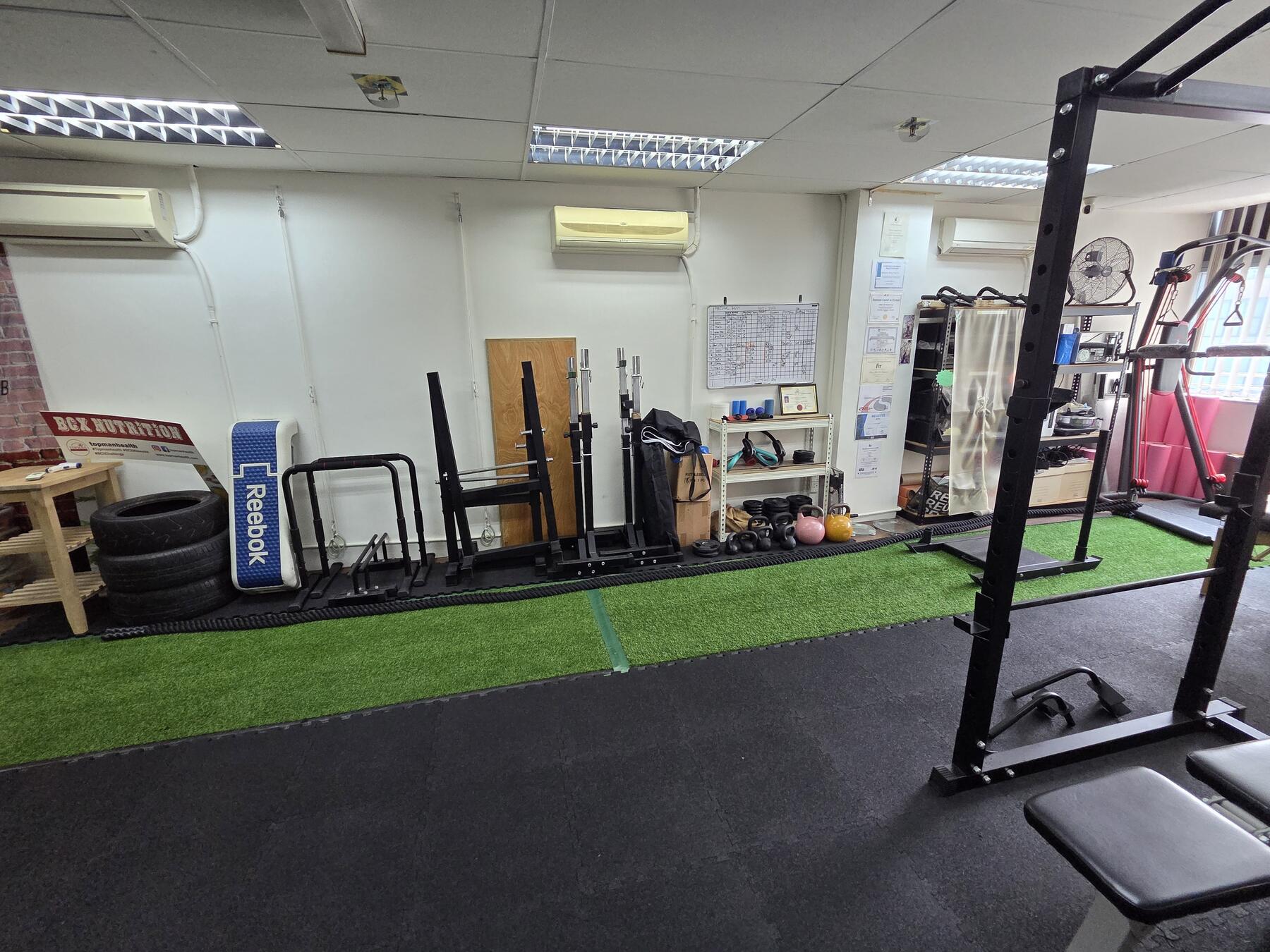 Main training floor at Topman Studio with power rack, benches, turf lane and functional wall